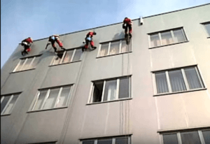 Echipa CuratArt.ro realizând servicii de alpinism utilitar pentru spălarea geamurilor, asigurând curățenie profesională la înălțime."